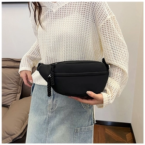 Detailed view of black nylon waist bag worn with a white casual top in a lifestyle setting