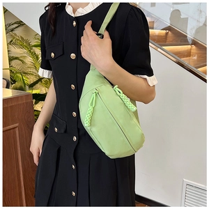 Detailed side view of a light green nylon crossbody bag on a model in a casual setting