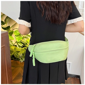 Detail of light green nylon fanny pack with braided cord zippers and adjustable strap