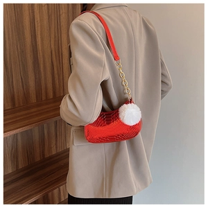 Detail of red crocodile embossed shoulder bag with gold chain and white plush ball charm