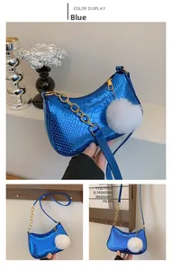 Detailed view of blue snakeskin embossed mini bag with gold chain and white pom pom
