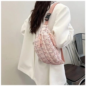Detail of pink plaid canvas waist bag with adjustable strap worn on a white blazer