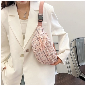 Detail of pink tweed chest bag with woven texture and nylon strap on white blazer