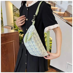 Detail of light green checkered crossbody bag with adjustable strap on a model indoors