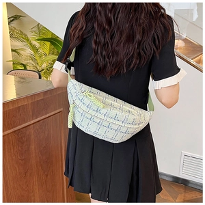 Plaid canvas saddle crossbody bag in light green and white worn as a chest pack