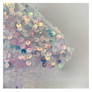 Vue macro de paillettes holographiques colorées sur un tissu blanc pour ce sac à bandoulière