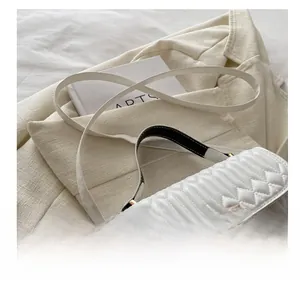 Detail of white quilted crossbody bag with pearl-embellished clasp and elegant gold hardware