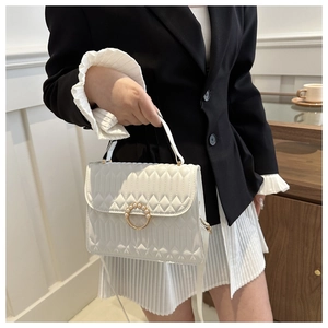 Detail of white quilted crossbody bag with pearl-inlaid golden buckle and sleek leather finish
