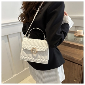 Close-up of a white quilted crossbody bag with pearl buckle and golden hardware detail