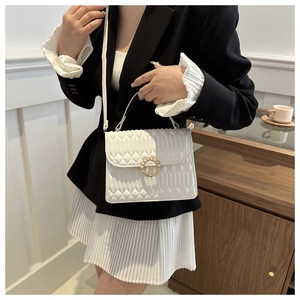 Elegant white quilted crossbody bag with pearl buckle shown with modern outfit