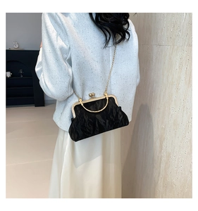 Détail d'un sac bandoulière plissé noir avec cadre doré et fermoir à billes
