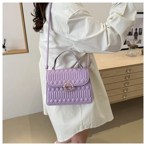 Detail of lavender quilted crossbody bag featuring a golden pearl ring buckle and leather texture