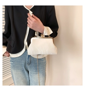 Détail du sac à main blanc en forme de coquillage avec poignée florale dorée et chaîne