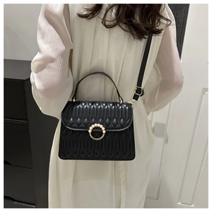 Detail of black quilted handbag with pearl-inlaid gold buckle and adjustable strap