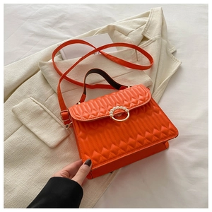 Close-up of orange quilted crossbody bag featuring a pearl-encrusted gold ring buckle