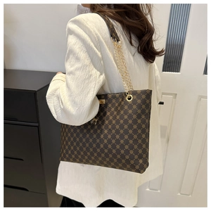 Detailed view of the gold chain strap and vintage pattern on a brown tote bag