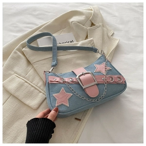 Dettaglio della borsa sottobraccio in denim blu con stella rosa e catena metallica