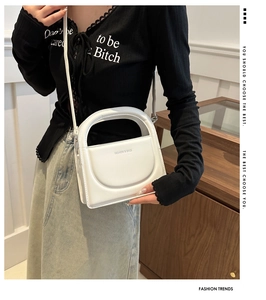 Detail of white minimalist handbag showing the matte texture and integrated handle