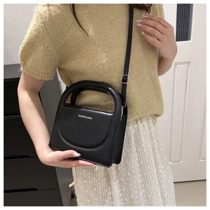 Close-up of black crossbody bag with FASHION & BAGS text on a model at waist level