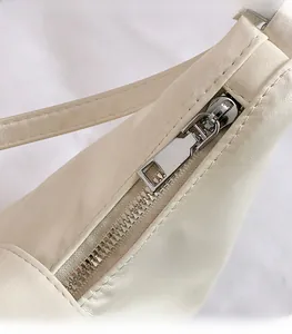 Detail of silver metal zipper and stitching on cream faux leather shoulder bag