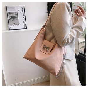 Close-up of pink PU leather tote featuring a silver metal bow and chain strap detail