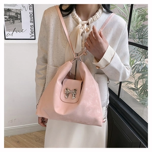 Pink soft PU leather shoulder bag with decorative silver metal bow on a creamy background