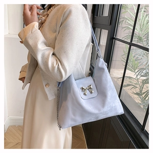 Light blue PU shoulder bag with silver bow buckle and chain strap shown on a model