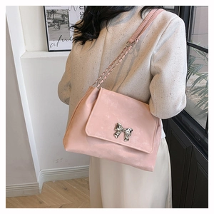 Close-up of pink chain shoulder bag with a decorative silver bow metal buckle detail