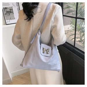 Detail of light purple soft PU tote bag with silver bow and chain strap on shoulder