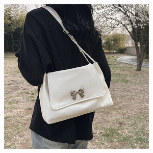Large white PU leather shoulder bag with metallic bow and chain strap in outdoor setting