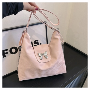 Detailed view of pink PU shoulder bag featuring a silver metal bow accent and chain strap