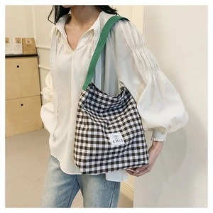 Détail du sac cabas en toile à carreaux avec bandoulière verte et étiquette EMIS