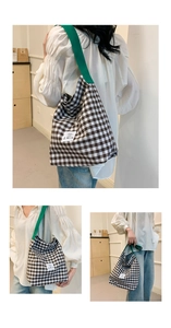 Detail of plaid tote bag with green shoulder strap and branded EMIS woven label