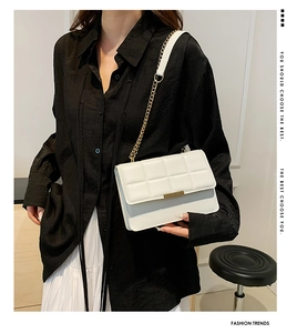 Detail of white quilted crossbody bag with golden chain strap on a fashion model