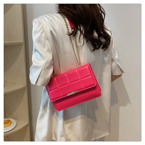Detail view of hot pink crossbody bag with quilted texture and gold chain strap
