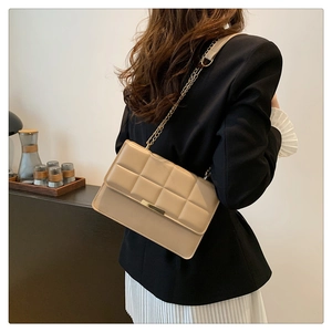 Detail of beige quilted chain bag shown from back view on model with black suit