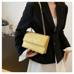 Model wearing a yellow quilted chain bag with gold metal hardware and flap closure