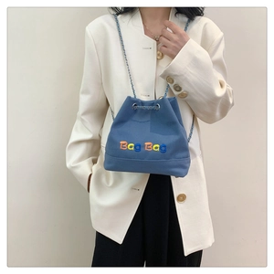 Sac seau en toile bleue avec broderie colorée et bandoulière chaîne sur mannequin