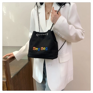 Sac seau en toile noire avec broderie Bag Bag et bandoulière chaîne porté par un mannequin