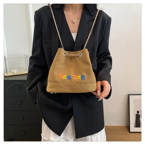 Détail d'un sac seau en toile kaki avec broderie Bag Bag et bandoulière en chaîne dorée