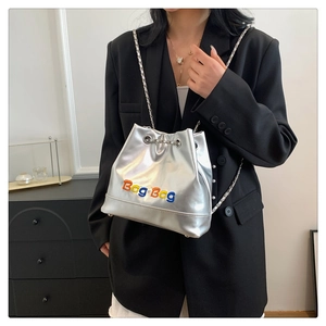 Détail du sac seau métallisé argenté avec patchs Bag Bag colorés et bandoulière chaîne