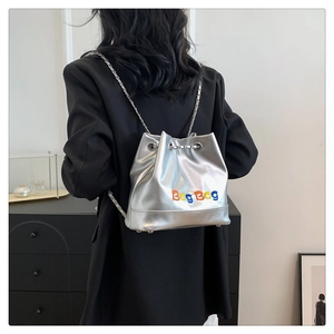 Détail du sac seau métallisé argenté avec broderie colorée sur un mannequin femme