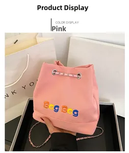 Détail du sac seau en toile rose avec broderie colorée et bandoulière en chaîne
