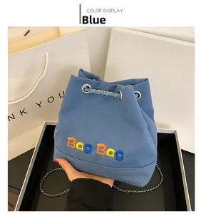 Détail du sac seau en toile bleue avec broderie Bag Bag et bandoulière en chaîne métal