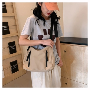 Asian model wearing a large beige nylon tote bag with black zippers and wide strap