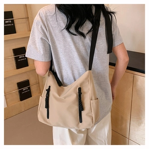 Detail of khaki nylon crossbody bag showing the adjustable strap and side pocket design