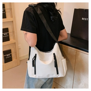 Detail view of large white tote bag with dual black zippers and wide shoulder strap