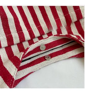 Detailed close-up of a red and white striped canvas bucket bag with silver magnetic closure
