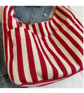 Detailed close-up of the red and white striped canvas fabric texture on a hobo handbag