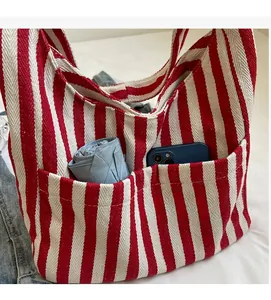 Detail of red and white striped canvas tote showing front pockets and storage capacity